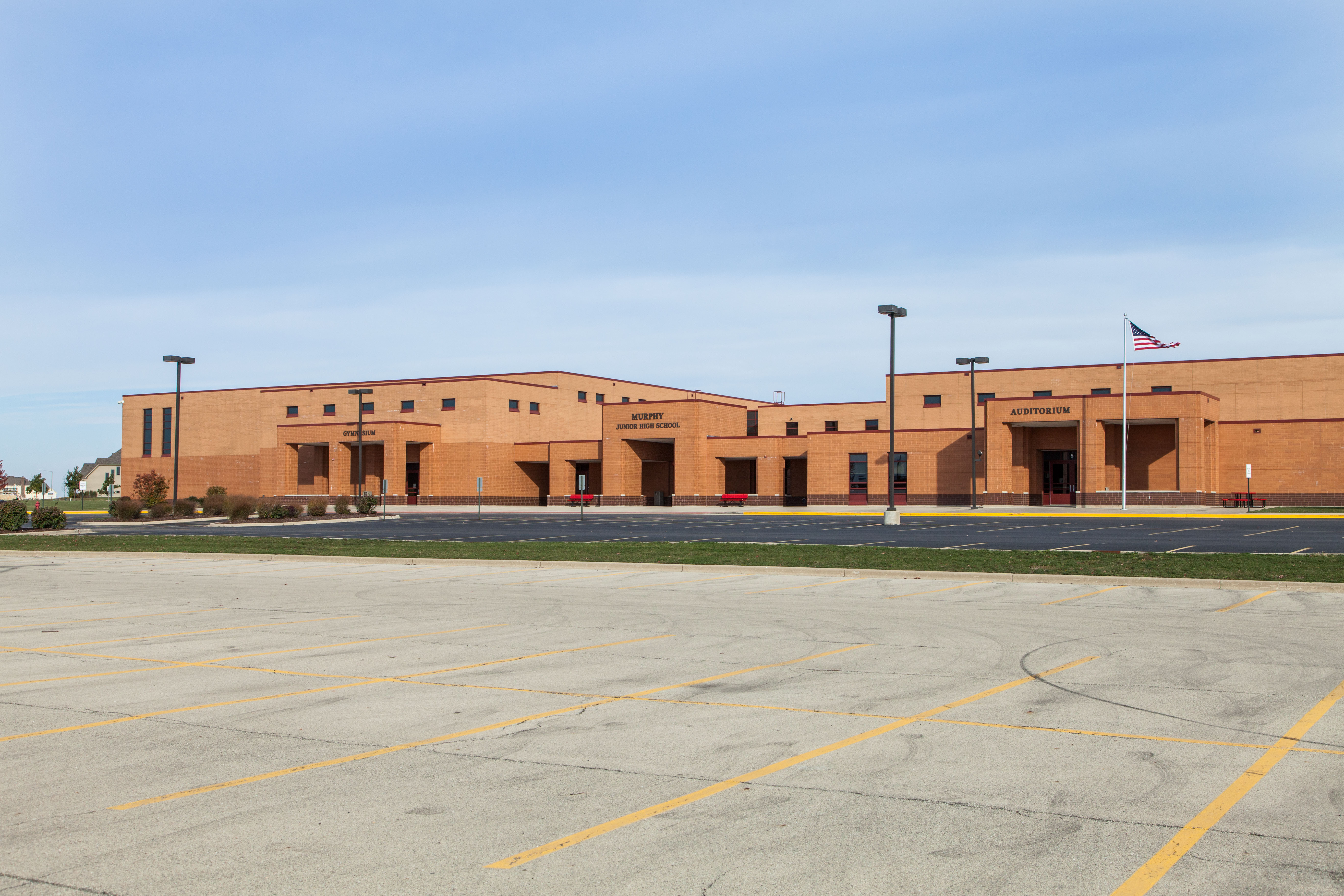 Front of Murphy building with parking lot, American flag, and blue sky. 